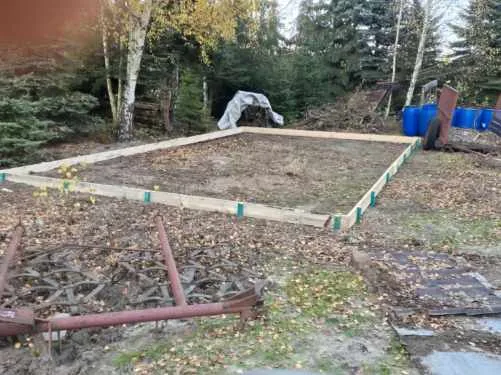 Zdjęcie przedstawia przygotowane fundamenty z drewnianą podbudową, stanowiące gotową podstawę do dalszych prac budowlany