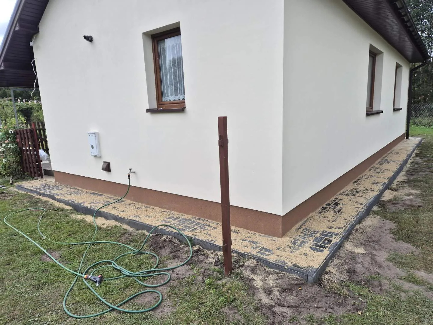 Dom w trakcie generalnego remontu z ukończoną białą elewacją i brązową podziałką